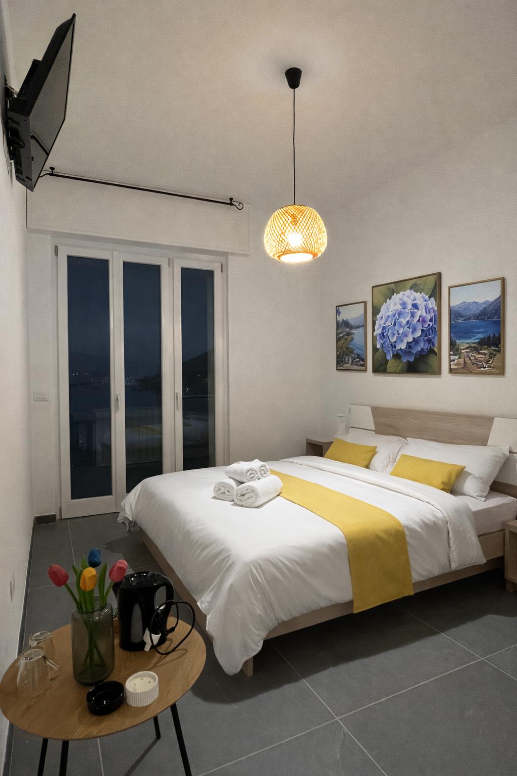 Camera Ortensia con letto matrimoniale, dettagli gialli e portafinestra sul balcone